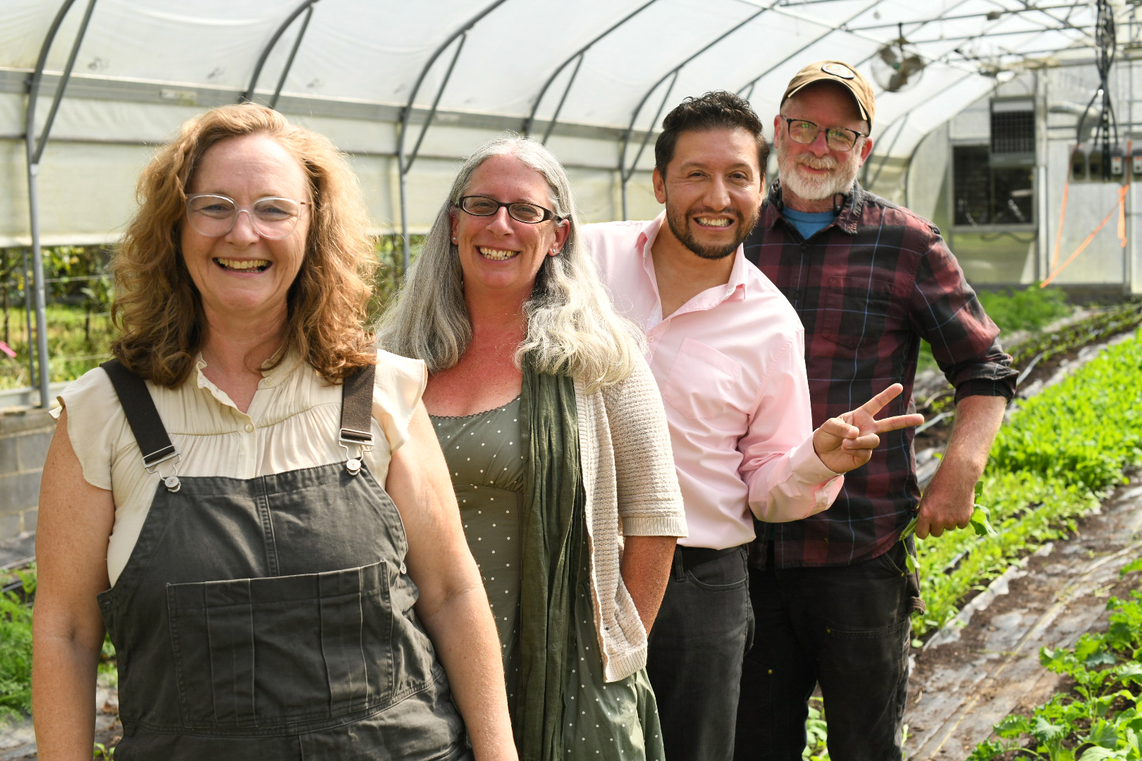 Four people standing together among crops in a greenhouse