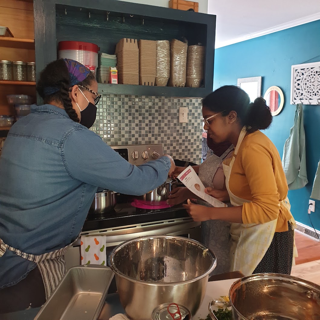 Neighbors cooking together at the stove in the Caja kitchen