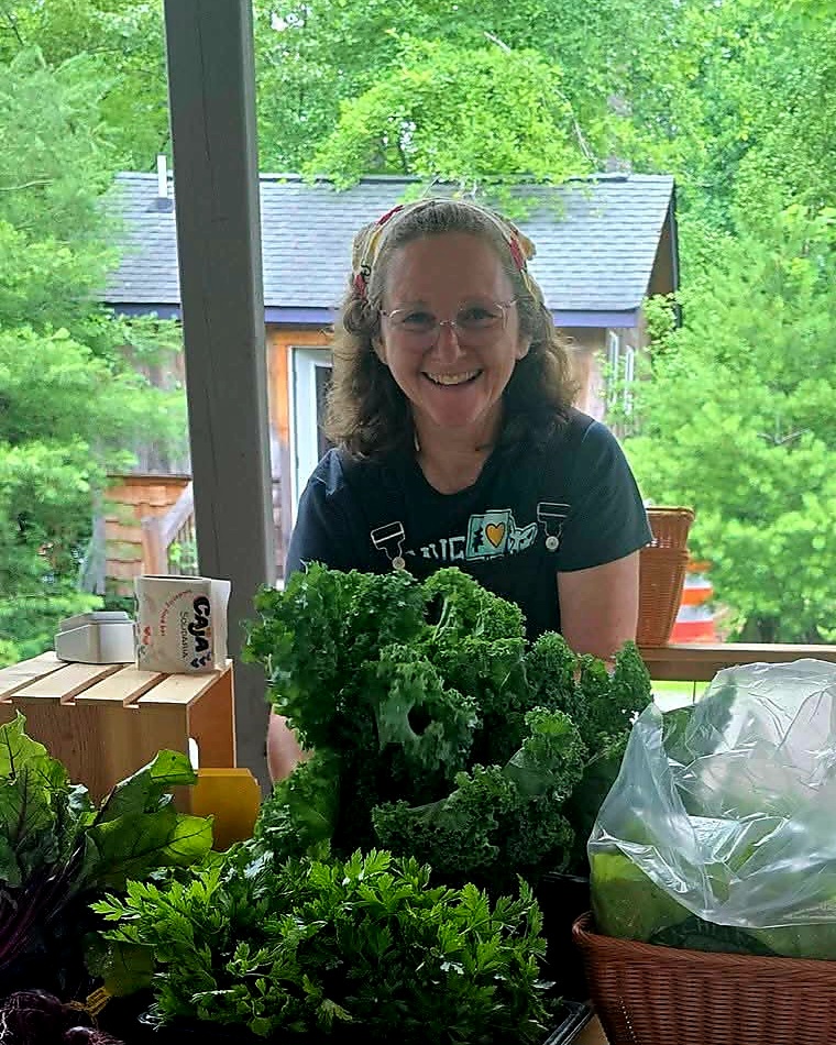 Sonya Jones smiling behind a table of fresh kale and parsley